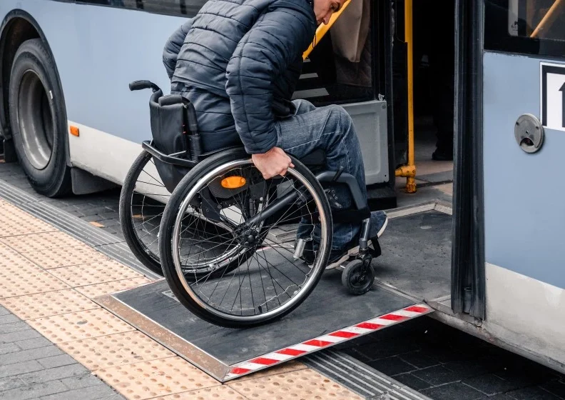 Disabled man in wheelchair using ramp to get on bus