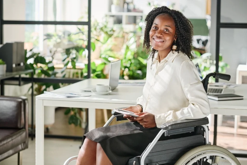 Happy woman in wheelchair smiling at the camera in office